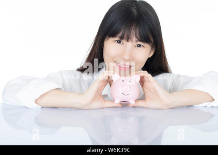 Weibliche putting Amicana Münzen und ein Viertel in ein Sparschwein auf weißem Hintergrund Stockfoto