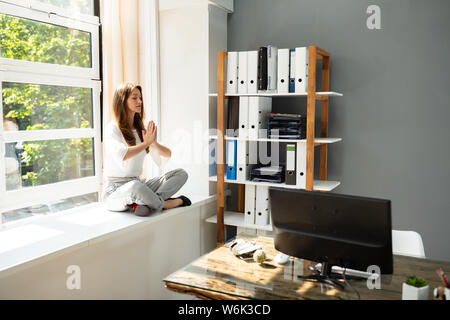 Geschäftsfrau über Kabinett Meditieren im Büro Stockfoto