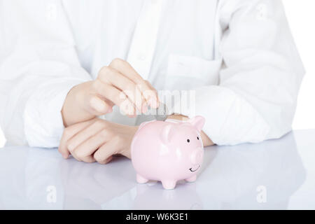 Weibliche hand Amicana Münzen und ein Viertel in ein Sparschwein auf weißem Hintergrund Stockfoto