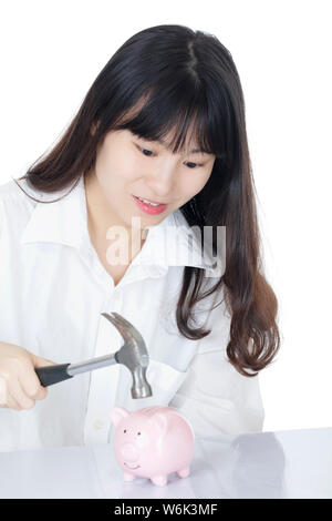 Frauen schlagen ein Sparschwein mit einem Hammer auf weißem Hintergrund Stockfoto