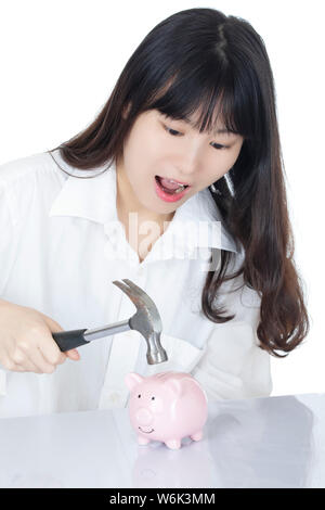 Frauen schlagen ein Sparschwein mit einem Hammer auf weißem Hintergrund Stockfoto