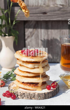 Pfannkuchen mit Beeren, Honig und Zutaten auf den Grau- und Holz- Hintergrund Stockfoto