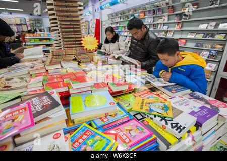 --FILE - ein chinesisches Kind und seine Eltern lesen Bücher in einer Buchhandlung in Lanzhou City, der ostchinesischen Provinz Jiangsu, 1. Januar 2015. Chinesische Kinder Stockfoto