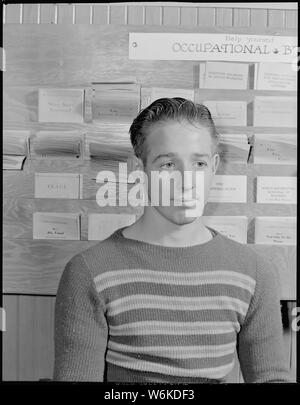 Roosevelt High School, Oakland, Kalifornien. High School Jugend. Von der High School im Juni 1939 graduierte, dieser Junge noch nicht durch Mai 1940 eingesetzt worden. In ein neues Leben Unlaunched, hat er an der High School Bibliothek zurück Zeit lesen aktuelle Zeitschriften zu töten und wieder die vertrauten und sicheren Umgebung eine Umgebung, in der er früher wohl war. Hinter ihm ist ein Rack der beruflichen Broschüren von der National Youth Administration ausgestellt Stockfoto