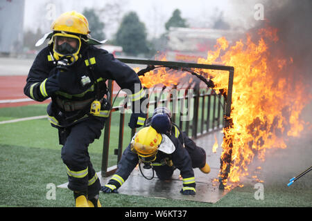 Chinesische Feuerwehrmänner kriechen durch Feuer loops während einer Schulung an einem Training in Chengdu City, im Südwesten Chinas Provinz Sichuan, 25 Jan Stockfoto