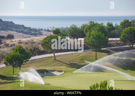 Sprinkler Bewässerungsanlage Arbeiten am grünen Golfkurs. Costa del Sol, Malaga, Spanien Stockfoto