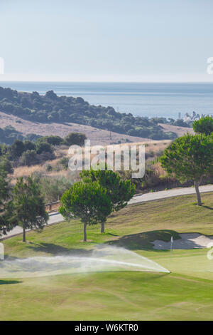 Sprinkler Bewässerungsanlage Arbeiten am grünen Golfkurs. Costa del Sol, Malaga, Spanien Stockfoto