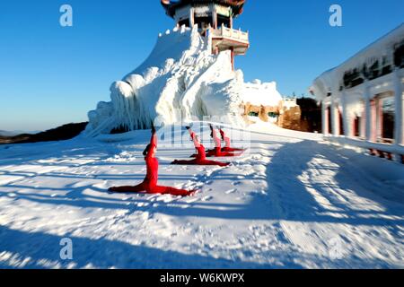 Chinesische Mädchen das Tragen der roten Yoga Kleidung yoga führen Sie vor Kälte an einem Ski Park in Luanchuan County, Luoyang City, Central China Provinz Henan, 11 J Stockfoto