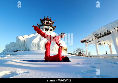 Chinesische Mädchen das Tragen der roten Yoga Kleidung yoga führen Sie vor Kälte an einem Ski Park in Luanchuan County, Luoyang City, Central China Provinz Henan, 11 J Stockfoto