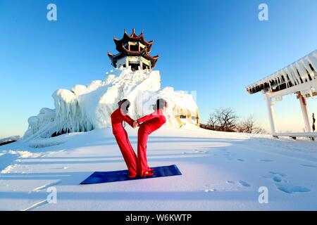 Chinesische Mädchen das Tragen der roten Yoga Kleidung yoga führen Sie vor Kälte an einem Ski Park in Luanchuan County, Luoyang City, Central China Provinz Henan, 11 J Stockfoto