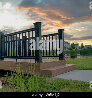 Square Bridge mit Holzdeck und schwarz Schutzgeländer, über einen kleinen und glänzenden Teich Stockfoto