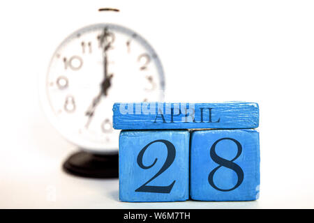 April 28 th. 28. Tag des Monats, handgefertigten Holz Würfel Kalender und Wecker auf blaue Farbe. Feder, Monat, Tag des Jahres Konzept. Stockfoto