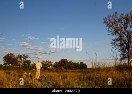 Makoro mit Touristen im Okavango Delta, Botswana, Verschieben in einen Kanal zwischen Reed Banken. Stockfoto