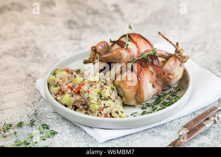 Köstliche gebackene Wachteln mit Speck und Beilage. Stockfoto