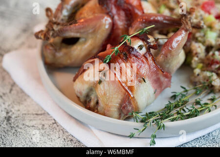 Köstliche gebackene Wachteln mit Speck und Beilage. Stockfoto