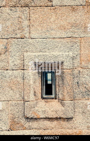 Vorderansicht des Granit stein Wand mit einem kleinen Fenster Stockfoto
