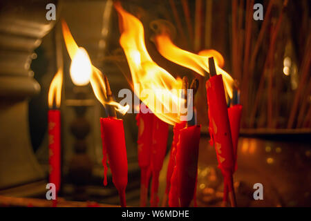 Brennende rote Kerzen schließen sich innerhalb der traditionellen chinesischen Tempel. Kerze Flamme. Makro Stockfoto