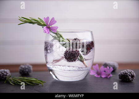 Gin und Tonic mit Brombeeren, einen Zweig Rosmarin und eine Blume von ornament Stockfoto