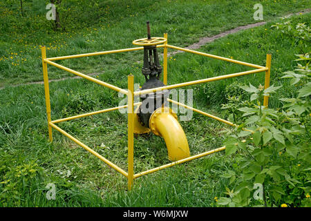 Große Gas Ventil an der Gasleitung außerhalb der grünen Gras und Sträuchern im Frühling Stockfoto