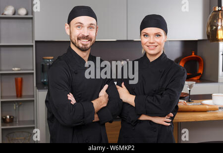 Porträt von zwei zuversichtlich persönliche Köche in der modernen Inneneinrichtung der privaten Küche stehend Stockfoto