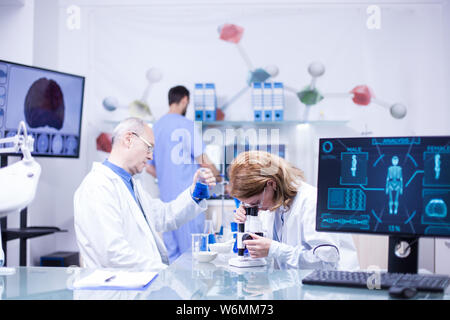 Team von Wissenschaftler in zusammen Arbeit im Labor. Leitender Chemiker mit Reagenzglas in der Hand. Stockfoto