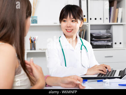 Asiatische Frau Doktor arbeiten mit Patienten in medizinischen Büro mit Laptop Stockfoto