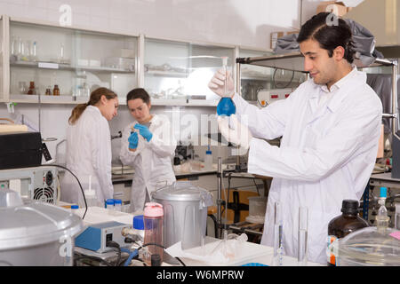 Feine männliche Chemiker im Labor arbeiten, die Analyse von flüssigen Proben in versuchsfläschchen Stockfoto