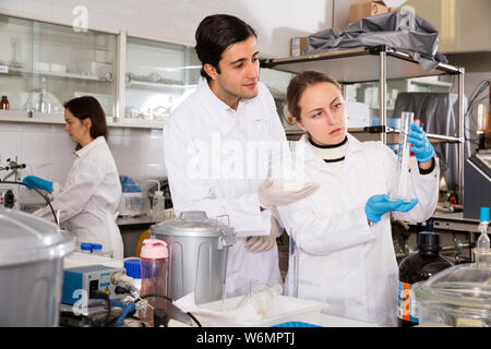 Portrait von Studenten die Prüfung chemischer Substanzen in Glas lab Kolben und Diskutieren bei der Durchführung von Experimenten im Labor der Universität Stockfoto