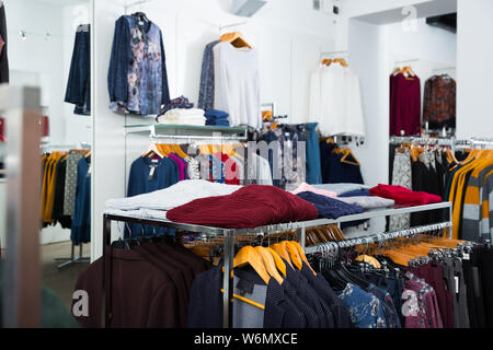 Innenraum der Kleidung Shop mit Blusen und cardigans auf Kleiderbügeln und Regale Stockfoto