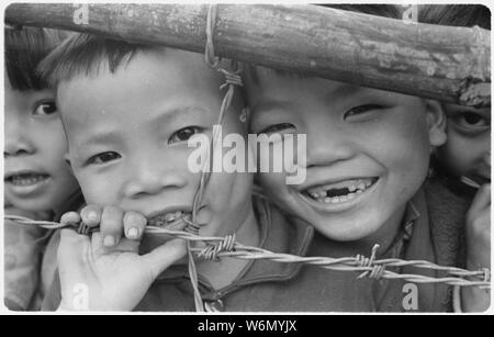 Vietnam.... vietnamesische Kinder der Phong Dien Flüchtling Weiler Peer durch einen Zaun. Es gibt 126 Familien, 10 Schwestern, 250 Kinder von 6 Jahre bis 15, und 115 Kinder unter 6 Jahren im Dorf. Stockfoto