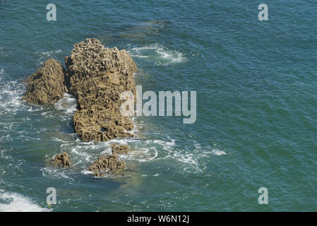 Wellen um Felsen im türkisblauen Meer auf der schönen, felsigen Küste von Pembrokeshire, Wales Stockfoto