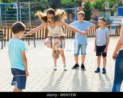 Glückliche Kinder Überspringen auf chinesische Springen elastische Kordel im Hof Stockfoto