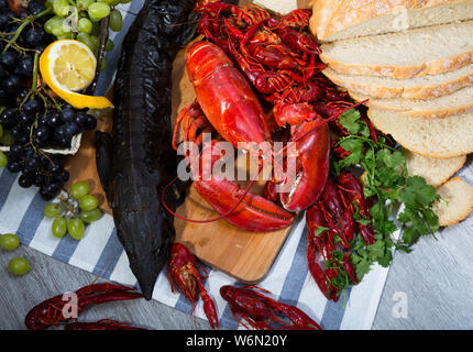 Appetitlich geräucherter Stör und gekochte Hummer mit crayfishes, Brot, Käse und Früchte auf Holz- Oberfläche Stockfoto