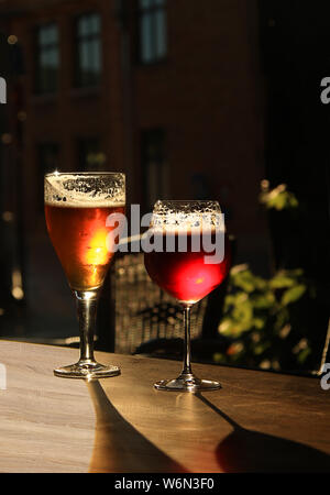 Zwei Gläser mit kaltem Bier und Apfelwein auf hölzernen cafe Tabelle. Dunkel Unschärfe Hintergrund mit Kopie Raum Stockfoto