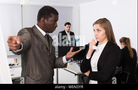Zornigen Mann Chef pointinting zu vermisst in der Arbeit zu weiblicher Manager arbeiten im Büro Stockfoto