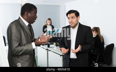 Zornigen Mann Chef pointinting zu vermisst in der Arbeit zu Mann Manager arbeiten im Büro Stockfoto