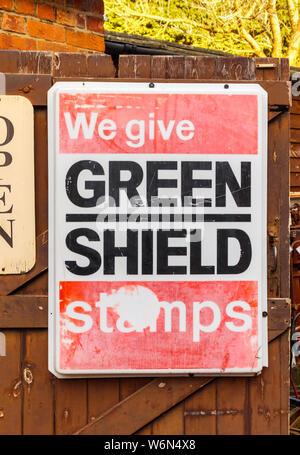 Vintage rot und weißem Kunststoff Werbung sign grüne Schild Briefmarken in ein Antiquitätengeschäft in Hungerford, einer historischen Stadt in Berkshire, England Stockfoto