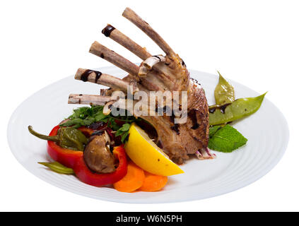 Gebratene Rack von Hammel mit gebackenem Gemüse, Pilzen, frischen Grüns, Zitrone und Balsamico Sauce Stockfoto