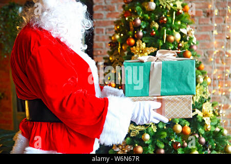 Santa Claus insgeheim anbringen Geschenkboxen durch den Weihnachtsbaum. Weihnachten Stockfoto