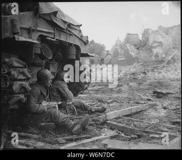 Mit deutschen Schalen schreien Overhead, Amerikanische Infanteristen suchen Schutz hinter einem Panzer. Im Hintergrund können die Ruinen der Stadt Geich, Deutschland, die immer noch unter schweren Beschuss wird gesehen werden.; Allgemeine Hinweise: Verwenden Sie Krieg und Konflikt Nummer 1090 bei der Bestellung eine Reproduktion oder Anforderung von Informationen zu diesem Bild. Stockfoto