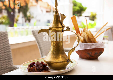 Arabischer Kaffee in einem traditionellen Türke mit Termine und Snacks in einem Tontopf Stockfoto