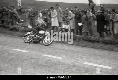 1950, historische, ein Motorradfahrer reiten in der TT Rennen auf der Isle of Man Die berühmten TT (Tourist Trophy) Motorradrennen begain in 1907 und über öffentliche Straßen der Insel, auf der Snaefell Mountain Course, obwohl zwischen 1954-1959, die Rennen auf der Cylpse Kurs mit traditionellen vollen Grid gestartet wurden. Stockfoto