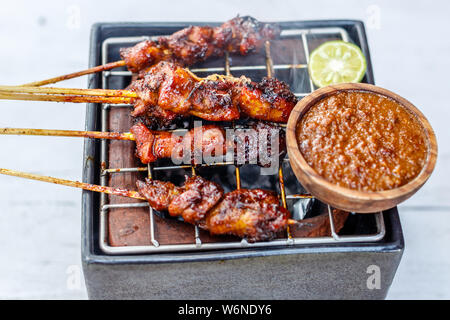 Sate Ayam (Hähnchen Sate, gegrilltes Fleisch auf Bambus Spieße), traditionelle indonesische Gerichte, serviert mit Sambal kacang, Erdnuß-Sauce. Bali, Indonesien. Stockfoto