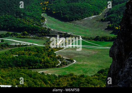 Serpentine Bergstraßen auf weißen Sand unter den Wald. Luftaufnahme Stockfoto