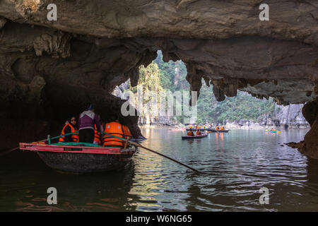 Ha Long Bay, Vietnam - 24. Dezember 2013: kleine Boote mit Touristen gehen durch einen cavecaves Stockfoto