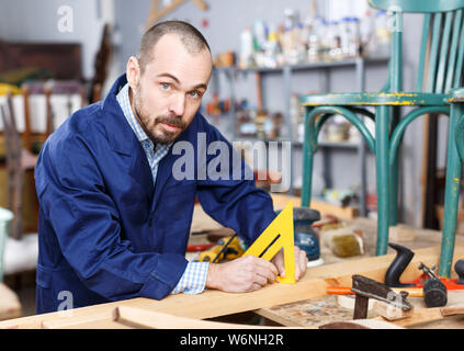 Männliche Tischler aus Dreieck Lineal zur Messung von Holz- Teil im Möbel Fachwerkstatt Stockfoto