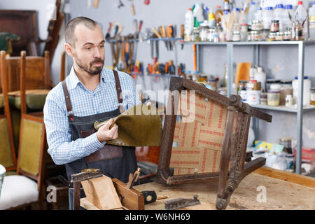 Professionelle männliche Tischler polstern Vintage Sessel in der Werkstatt Stockfoto