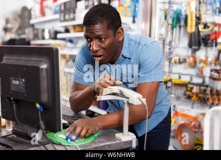 Schockiert nach Verkäufer hinter Zähler im Haushaltswaren Shop, computer monitor suchen Stockfoto