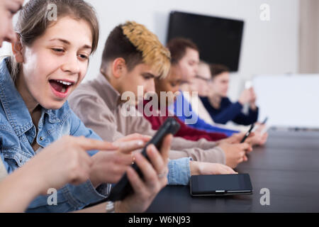 Positive Mitschüler über ihre Smartphones intensiv während der Klassen Stockfoto