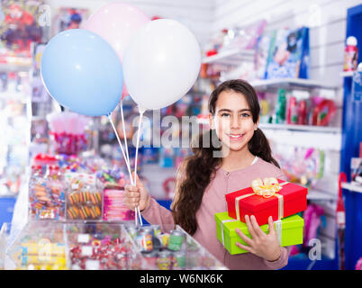 Lächelnd glücklich Fröhliche positive kleines Mädchen erhält Kartons mit Geschenken in der Spielzeug Shop Stockfoto